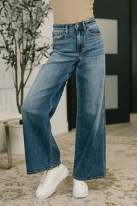 Person wearing blue jeans and white sneakers in an indoor setting