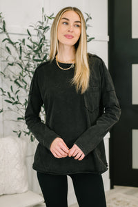Woman wearing a black long-sleeve shirt in an indoor setting with plants and decor.