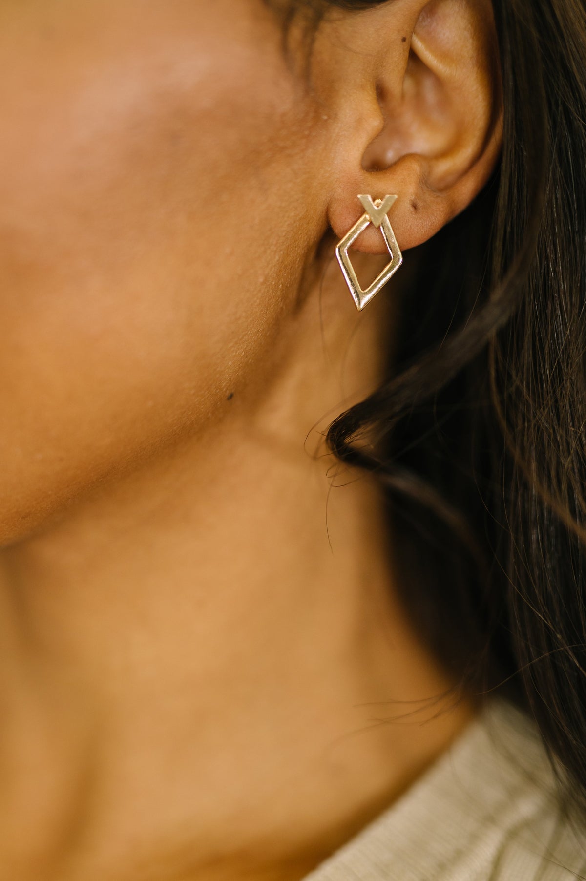 Close-up of a person wearing a gold geometric earring.