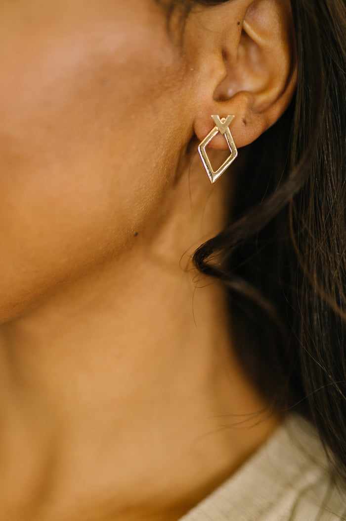 Close-up of a person wearing a gold geometric earring.