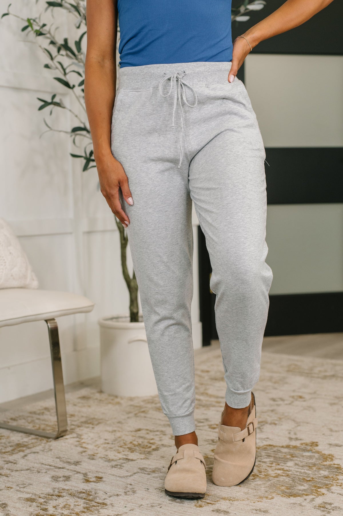 Person wearing gray sweatpants and a blue top in an indoor setting.