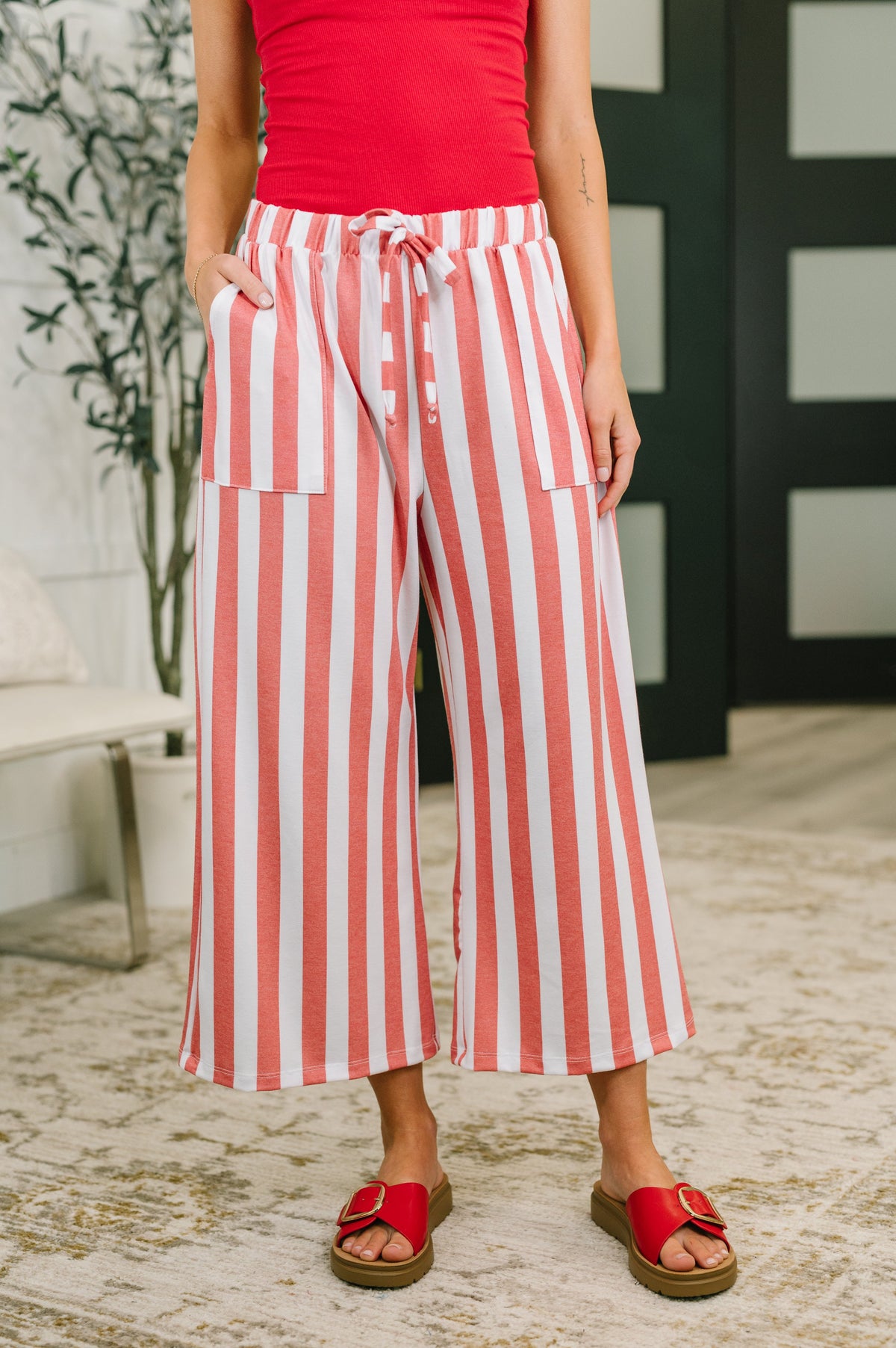 Person wearing red and white striped pants with a red top outdoors.