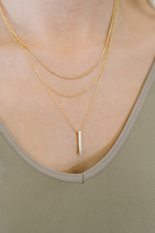 Gold necklaces on a person wearing a green top