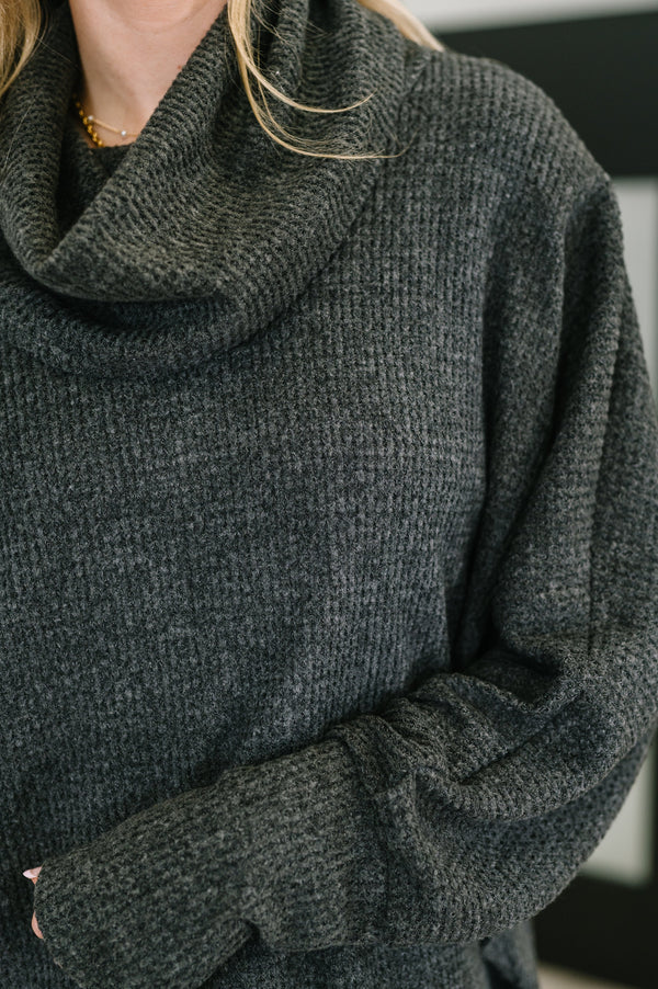 Dark gray sweater with a close-up on the sleeve and collar.