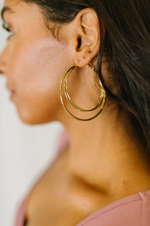 Close-up of a woman wearing gold hoop earrings with a blurred background