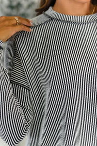 Close-up of a person wearing a black and white striped shirt with a blurred background