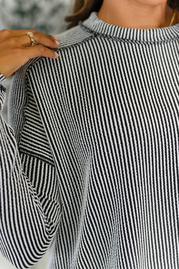 Close-up of a person wearing a black and white striped shirt with a blurred background