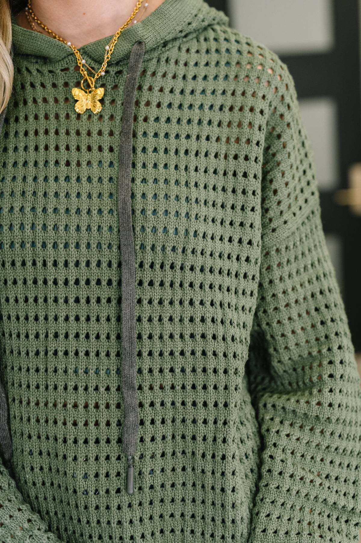 Green textured sweater worn by a person with a blurred background