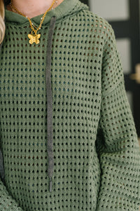 Green textured sweater worn by a person with a blurred background