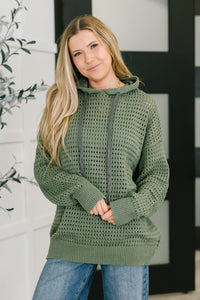 Woman wearing a green crochet hoodie with a neutral background