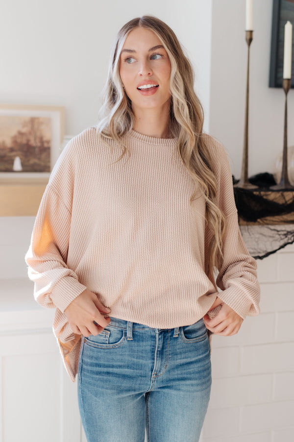 Woman wearing a beige sweater and blue jeans indoors