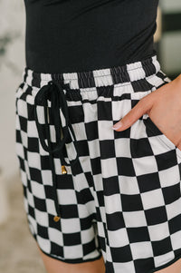 Black and white checkered shorts with a belt worn by a person.