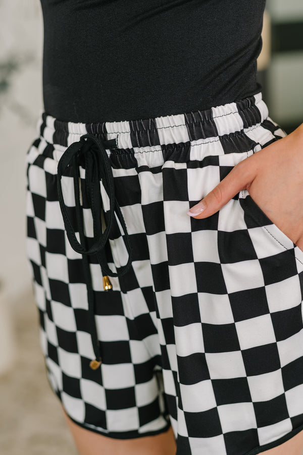 Black and white checkered shorts with a belt worn by a person.